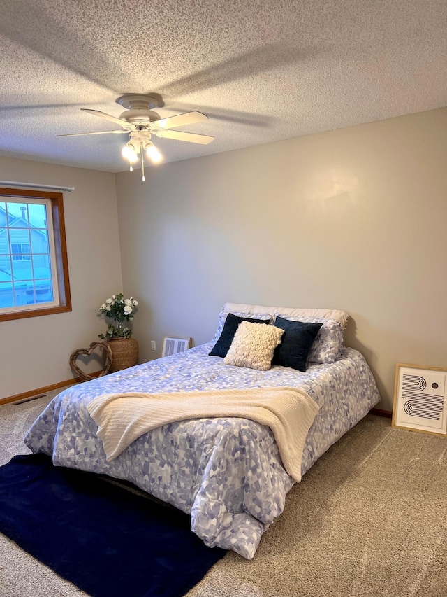 bedroom featuring heating unit, carpet, ceiling fan, and a textured ceiling