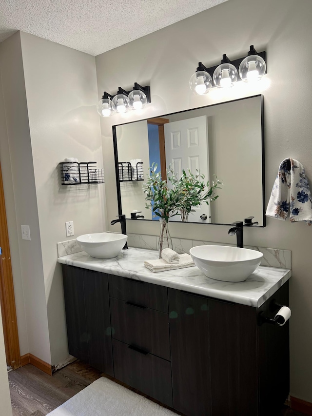 bathroom with a textured ceiling, wood-type flooring, and vanity