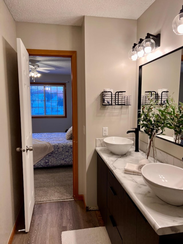 bathroom with a textured ceiling, hardwood / wood-style flooring, ceiling fan, and vanity