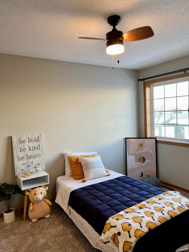 bedroom with ceiling fan, carpet floors, and a textured ceiling