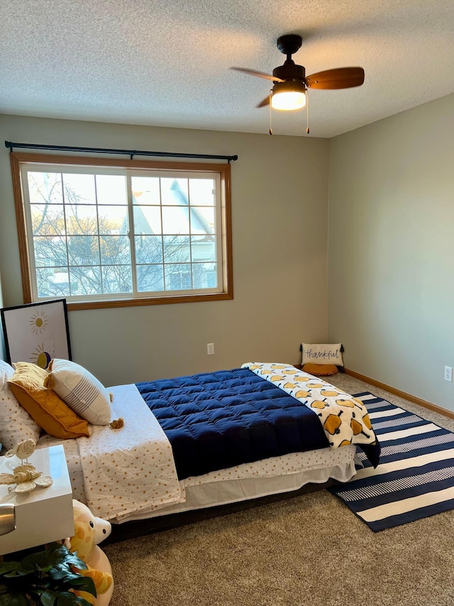 carpeted bedroom featuring multiple windows, a textured ceiling, and ceiling fan