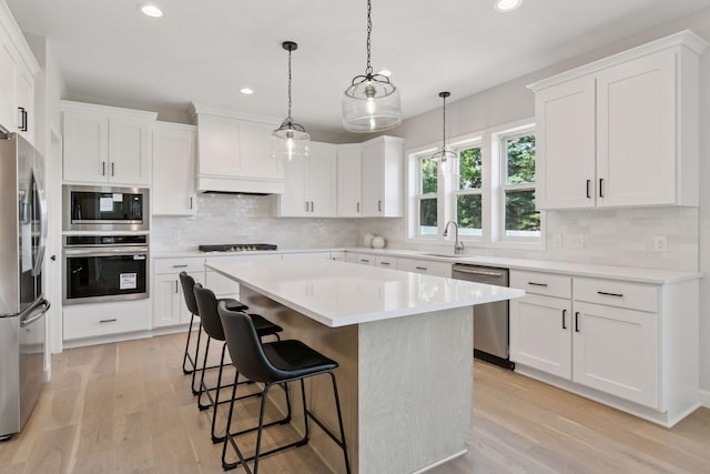 17953 Hidden Creek Trl, Lakeville, MN 55044 - kitchen featuring appliances with stainless steel finishes, light wood-style floors, a kitchen island, recessed lighting, and tasteful backsplash
