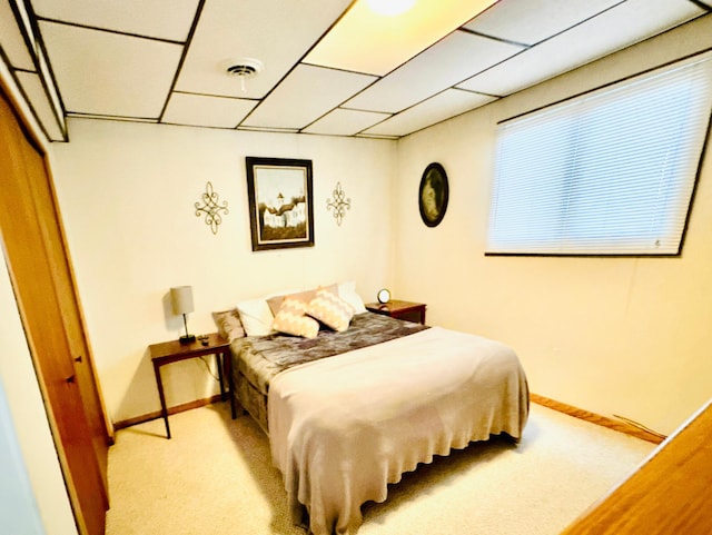 bedroom with a paneled ceiling and light colored carpet