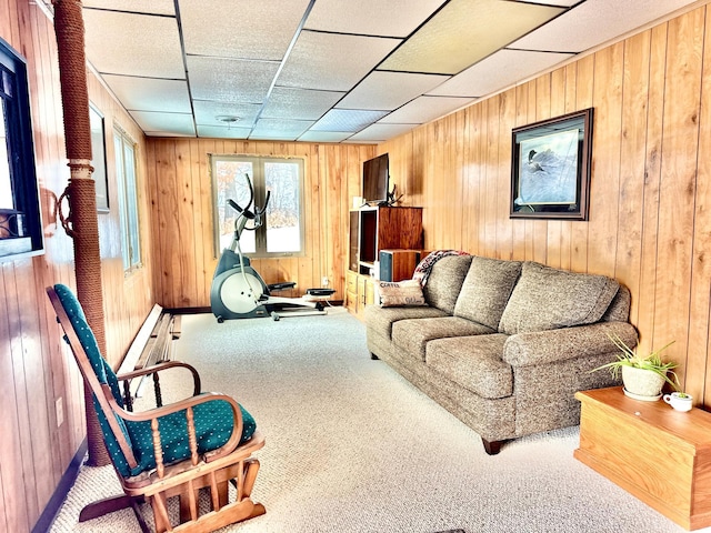 carpeted living room featuring wooden walls and a paneled ceiling