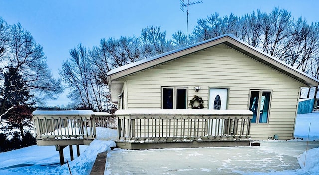 snow covered rear of property with a wooden deck