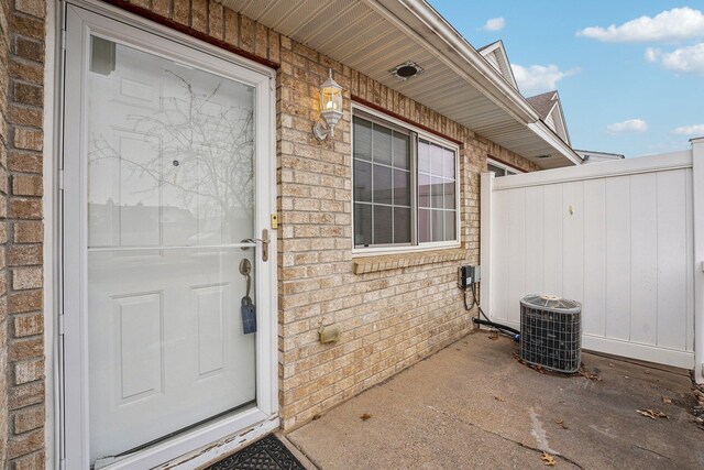 doorway to property with brick siding, a patio area, and cooling unit