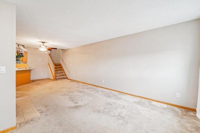 unfurnished living room featuring baseboards, carpet, stairway, and a textured ceiling