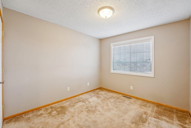 carpeted empty room with a textured ceiling, visible vents, and baseboards