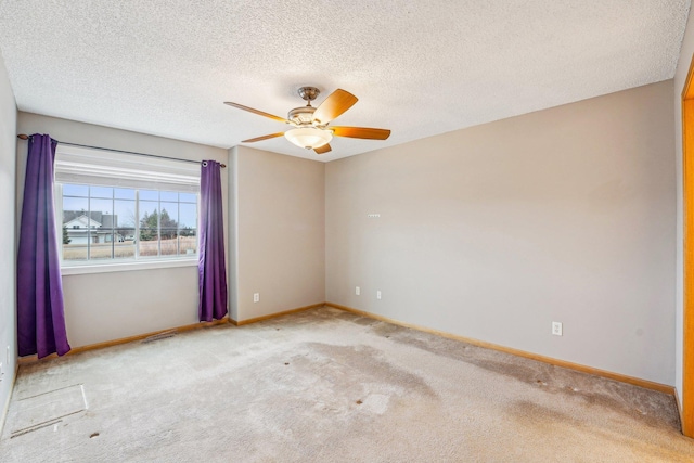 spare room featuring light carpet, a textured ceiling, baseboards, and a ceiling fan