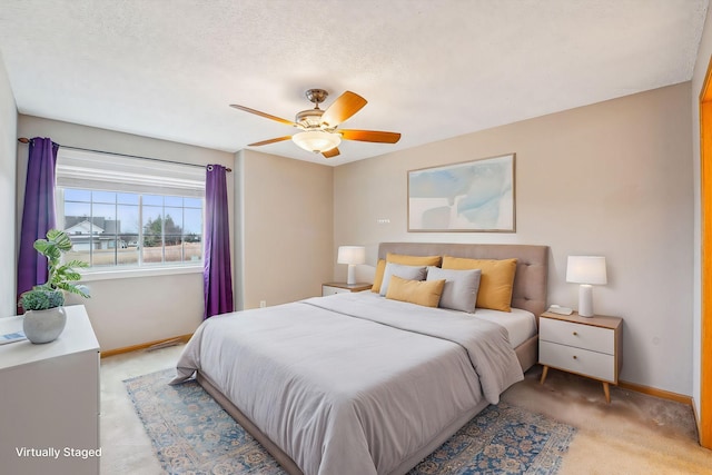bedroom featuring light carpet, ceiling fan, baseboards, and a textured ceiling