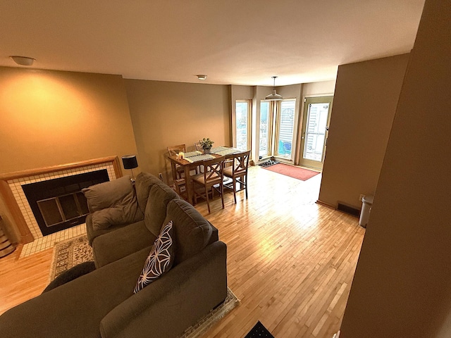 living room with a brick fireplace, visible vents, and light wood-style flooring