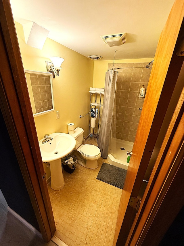 full bath featuring toilet, a stall shower, a sink, and visible vents