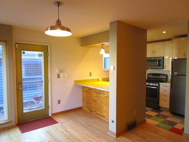 kitchen featuring appliances with stainless steel finishes, light wood-type flooring, a healthy amount of sunlight, and visible vents