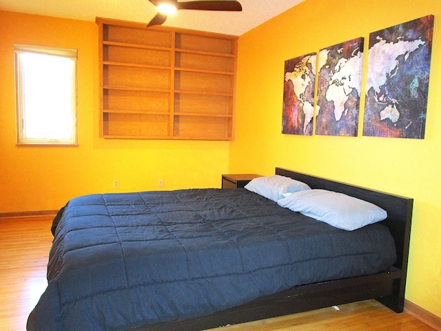 bedroom with ceiling fan, baseboards, and wood finished floors