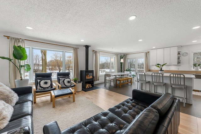 living area featuring recessed lighting, light wood-type flooring, a textured ceiling, and a wood stove