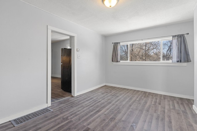 spare room featuring hardwood / wood-style flooring and a textured ceiling