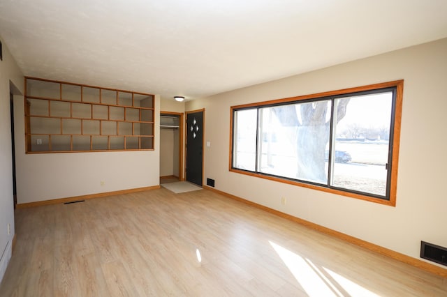 spare room featuring light wood-style floors, visible vents, and baseboards