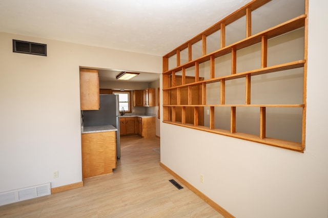 interior space featuring a sink, baseboards, visible vents, and light wood-type flooring