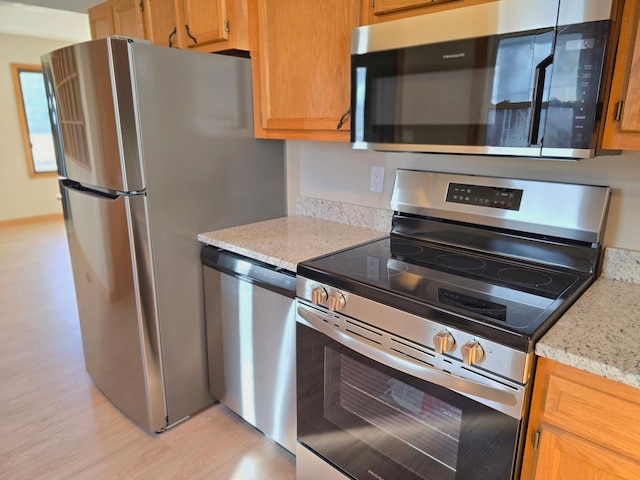 kitchen featuring light stone counters, light wood finished floors, and stainless steel appliances