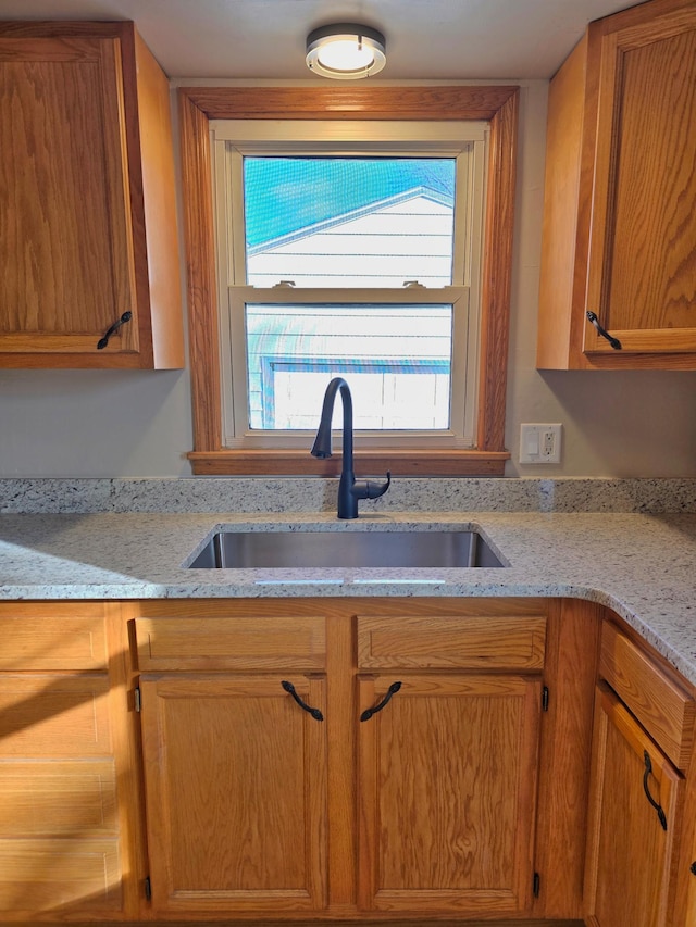 kitchen featuring light stone countertops and a sink