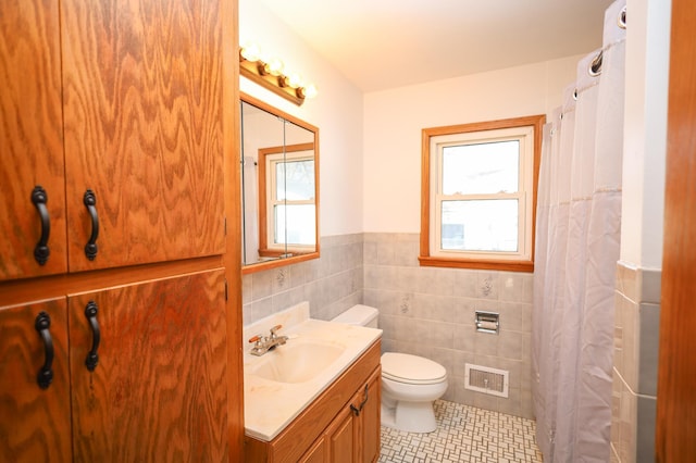 full bathroom with visible vents, plenty of natural light, toilet, and tile walls