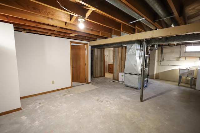 basement with heating unit, baseboards, and a sink