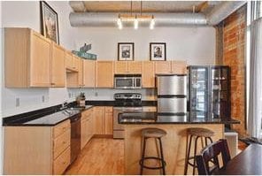 kitchen featuring stainless steel appliances, a center island, light brown cabinets, and a kitchen breakfast bar