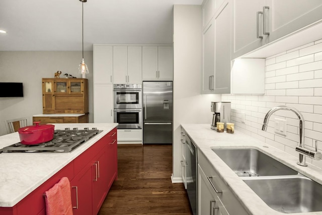 kitchen featuring dark wood finished floors, stainless steel appliances, light countertops, and a sink