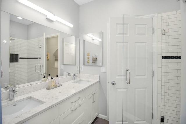 full bathroom featuring a sink, baseboards, double vanity, and a shower stall