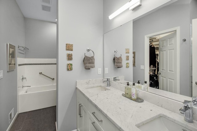 bathroom with a walk in closet, double vanity, visible vents, and a sink