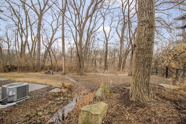 view of yard featuring central AC and fence