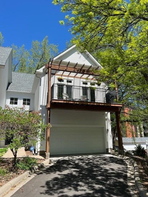 view of front of home featuring driveway, an attached garage, and a balcony