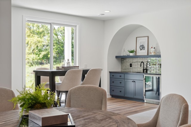 dining area with wine cooler, indoor bar, and light wood-type flooring