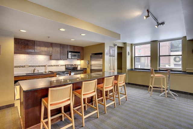 kitchen with a breakfast bar area, stainless steel appliances, a center island, decorative backsplash, and dark countertops