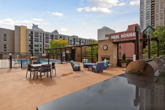 view of patio / terrace with a warm lit fireplace, a community pool, and fence