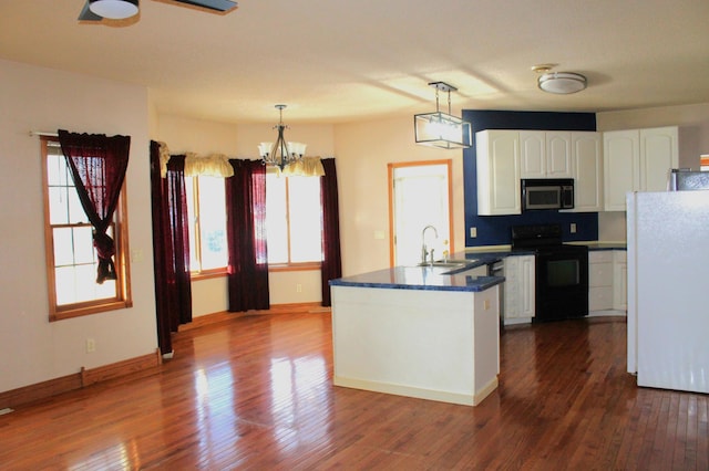 kitchen featuring white refrigerator, white cabinetry, black range with electric cooktop, and pendant lighting