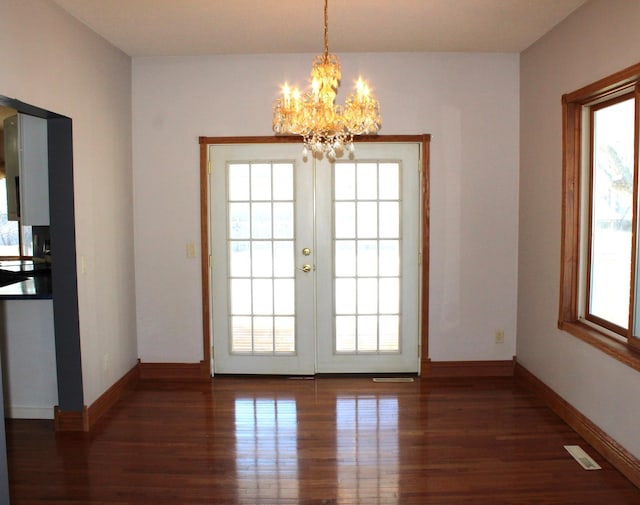 doorway with dark hardwood / wood-style floors, an inviting chandelier, and french doors