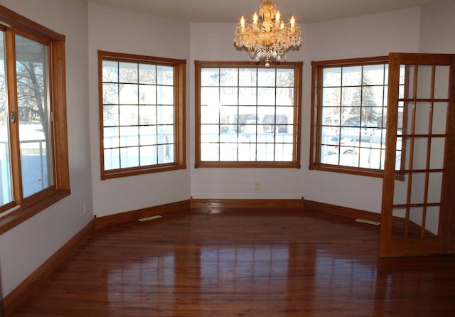 unfurnished dining area with a healthy amount of sunlight, dark hardwood / wood-style flooring, and a chandelier