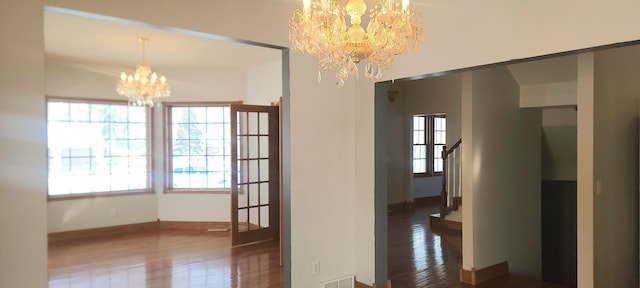 unfurnished dining area with a wealth of natural light, a notable chandelier, and dark hardwood / wood-style flooring