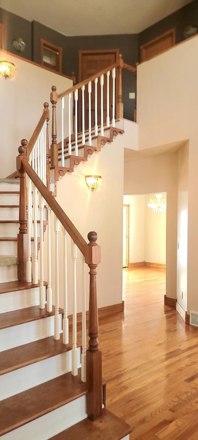 stairs featuring wood-type flooring and a high ceiling