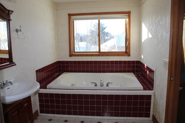 bathroom with a relaxing tiled tub, vanity, and tile patterned flooring