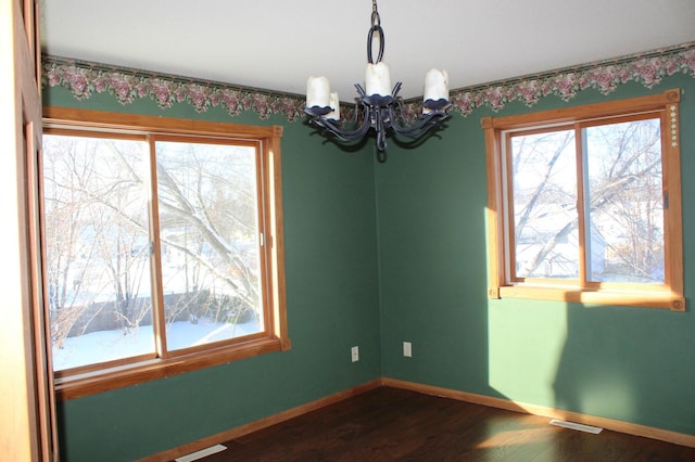 empty room featuring dark hardwood / wood-style flooring and an inviting chandelier