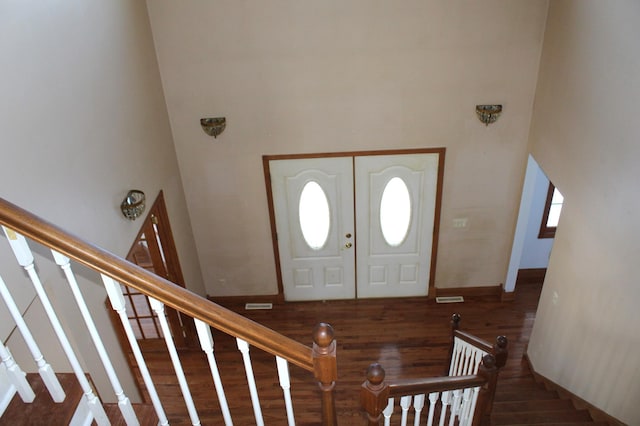 foyer entrance featuring dark hardwood / wood-style flooring and a towering ceiling