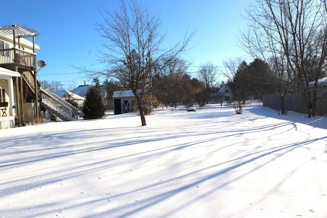 snowy yard featuring a shed