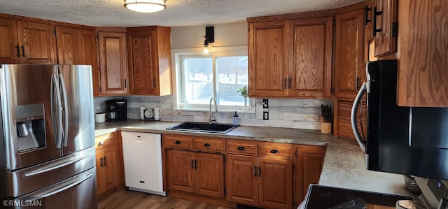 kitchen with sink, stainless steel fridge, white dishwasher, a textured ceiling, and decorative backsplash