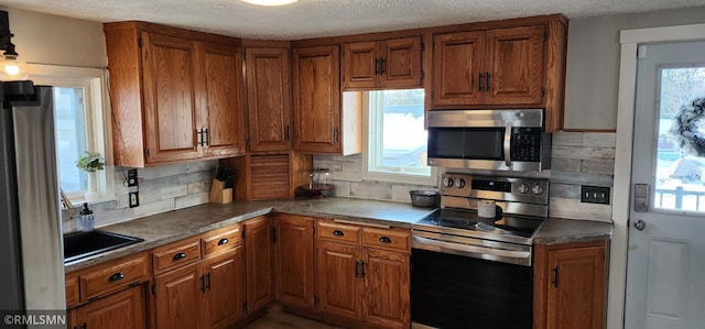 kitchen featuring decorative backsplash, a healthy amount of sunlight, appliances with stainless steel finishes, and a textured ceiling