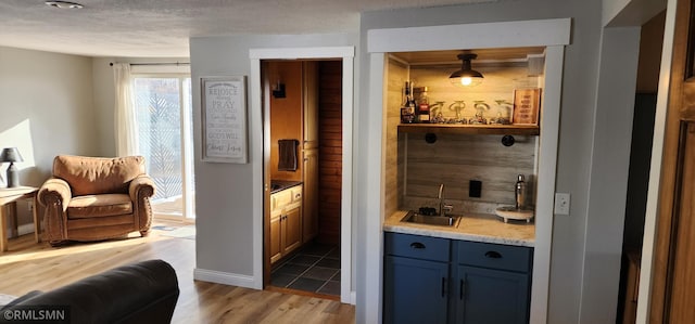 bar featuring hardwood / wood-style floors, sink, pendant lighting, and a textured ceiling