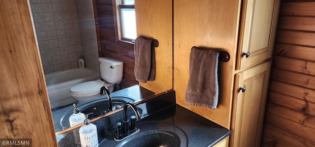 full bathroom featuring toilet, tiled shower / bath, wooden walls, and sink