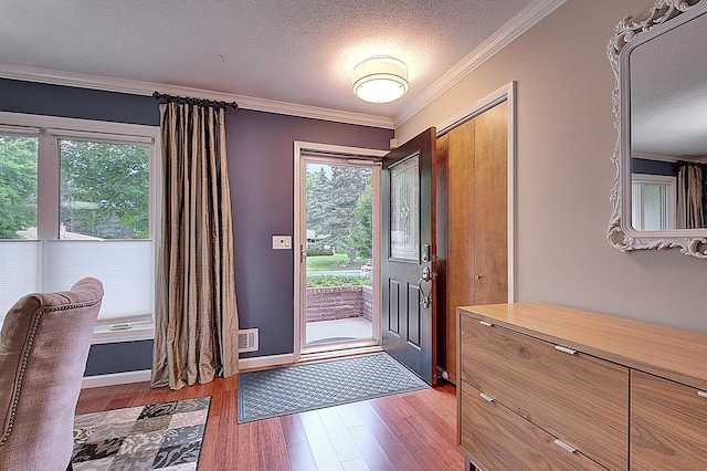 foyer entrance with a healthy amount of sunlight, ornamental molding, light hardwood / wood-style flooring, and a textured ceiling