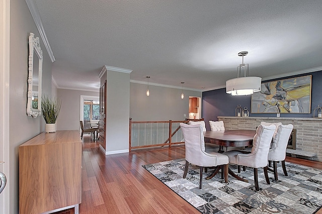 dining area featuring hardwood / wood-style flooring, ornamental molding, and a textured ceiling